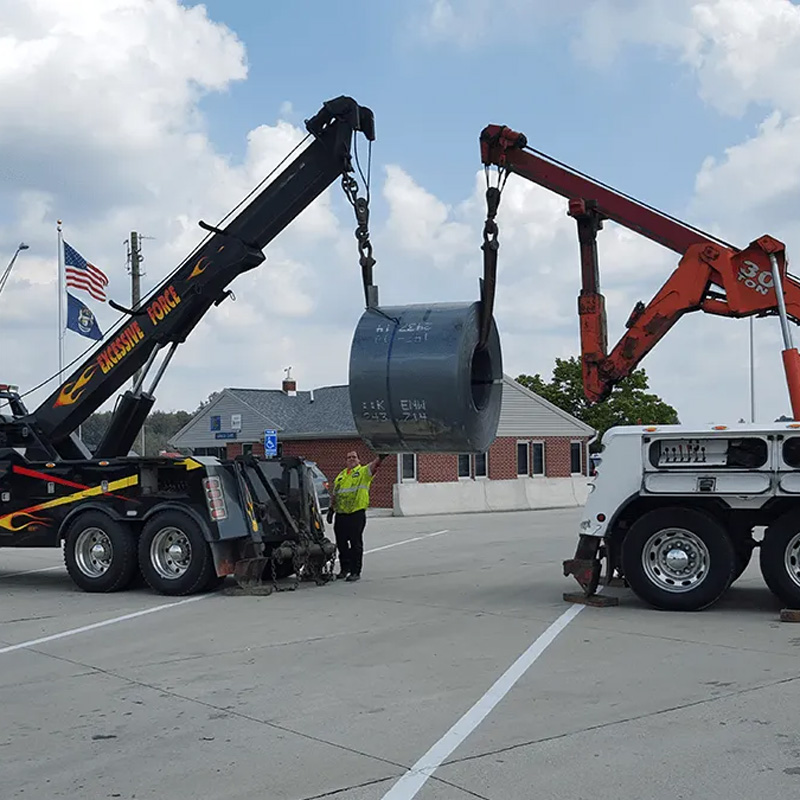 two tow trucks lifting steel